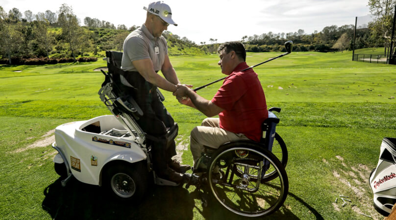 Consulting handicapped golfer using standing sports wheelchair.